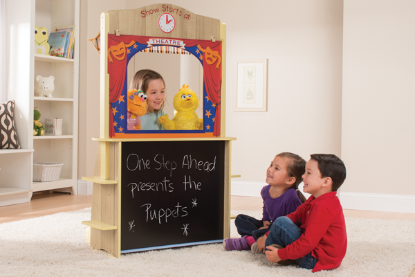 Young girl with puppets behind Kids' wooden play theater with chalk board front, and two smiling children watching.