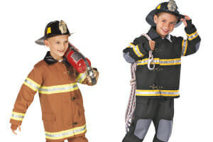 Two smiling boys dressed in fireman's outfits and hats, one in brown holding an extinguisher, and one in black with rope.