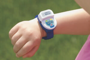 A young girl is looking at the Potty Watch on her wrist which helps to remind her to take potty breaks.