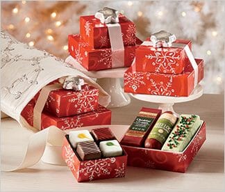 Food gift sets including a box of four petit fours with a box of a sausage log, a cheese bar and a torte.