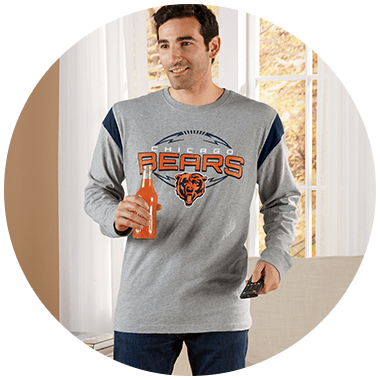 A man in a grey long sleeve Chicago Bears T-shirt holding a bottle of orange drink.
