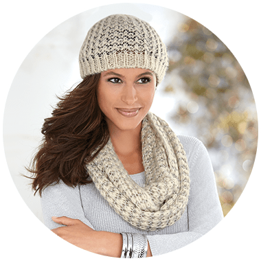Smiling brunette woman wearing a matching ecru knit hat and scarf.